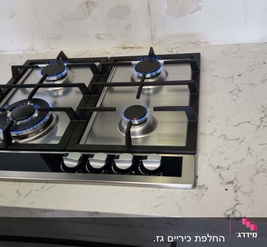 כיריים גז עם ארבעה מבערים על משטח שיש